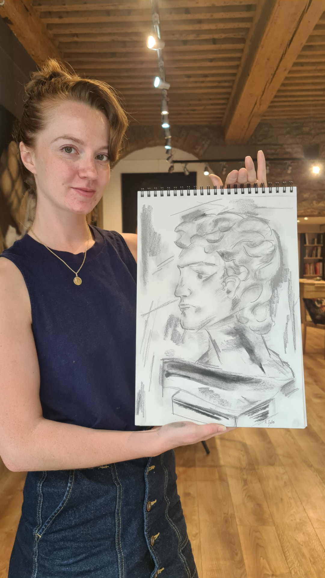 Élève présentant son dessin au fusain d'un buste antique