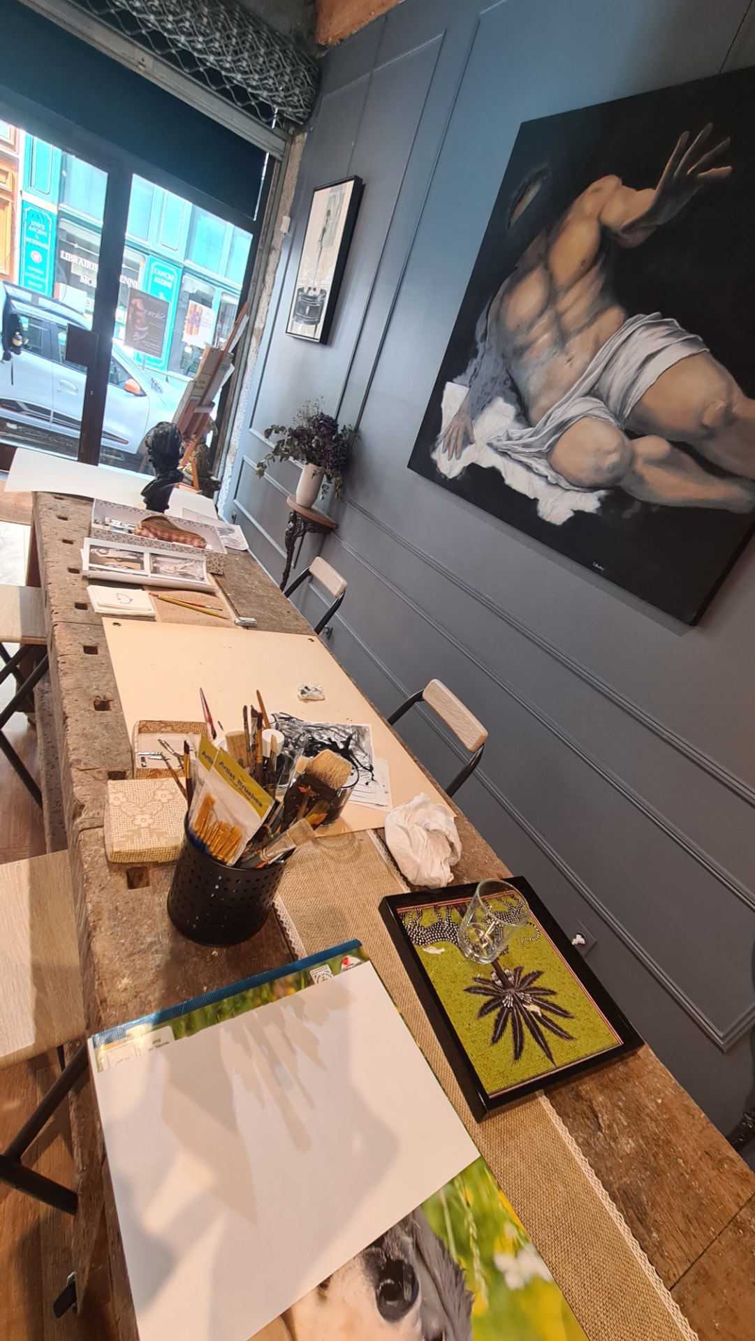 L'atelier : établi en bois, pinceaux et grande toile du corps