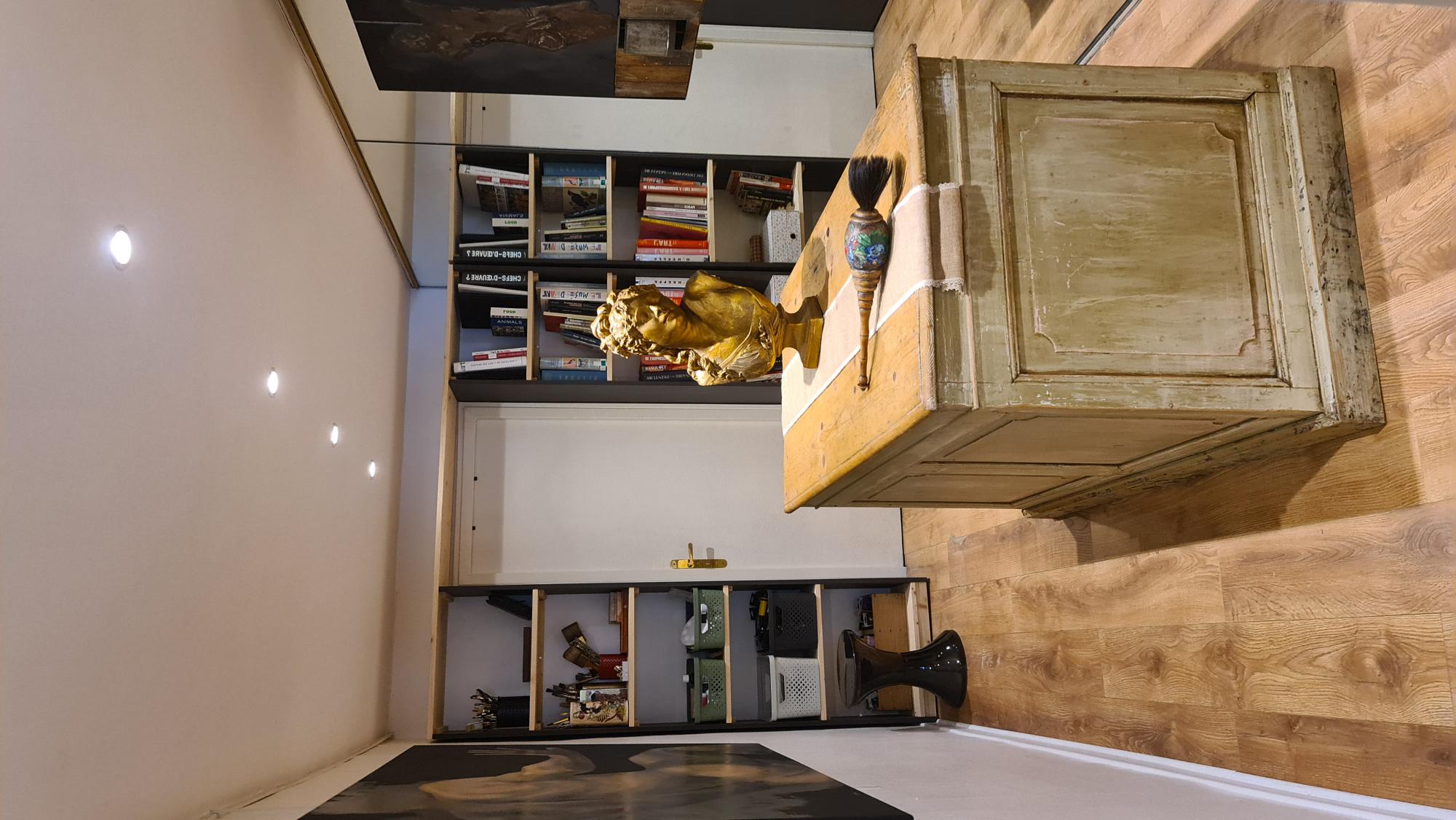 Second espace : bibliothèque, comptoir en bois patiné et buste doré