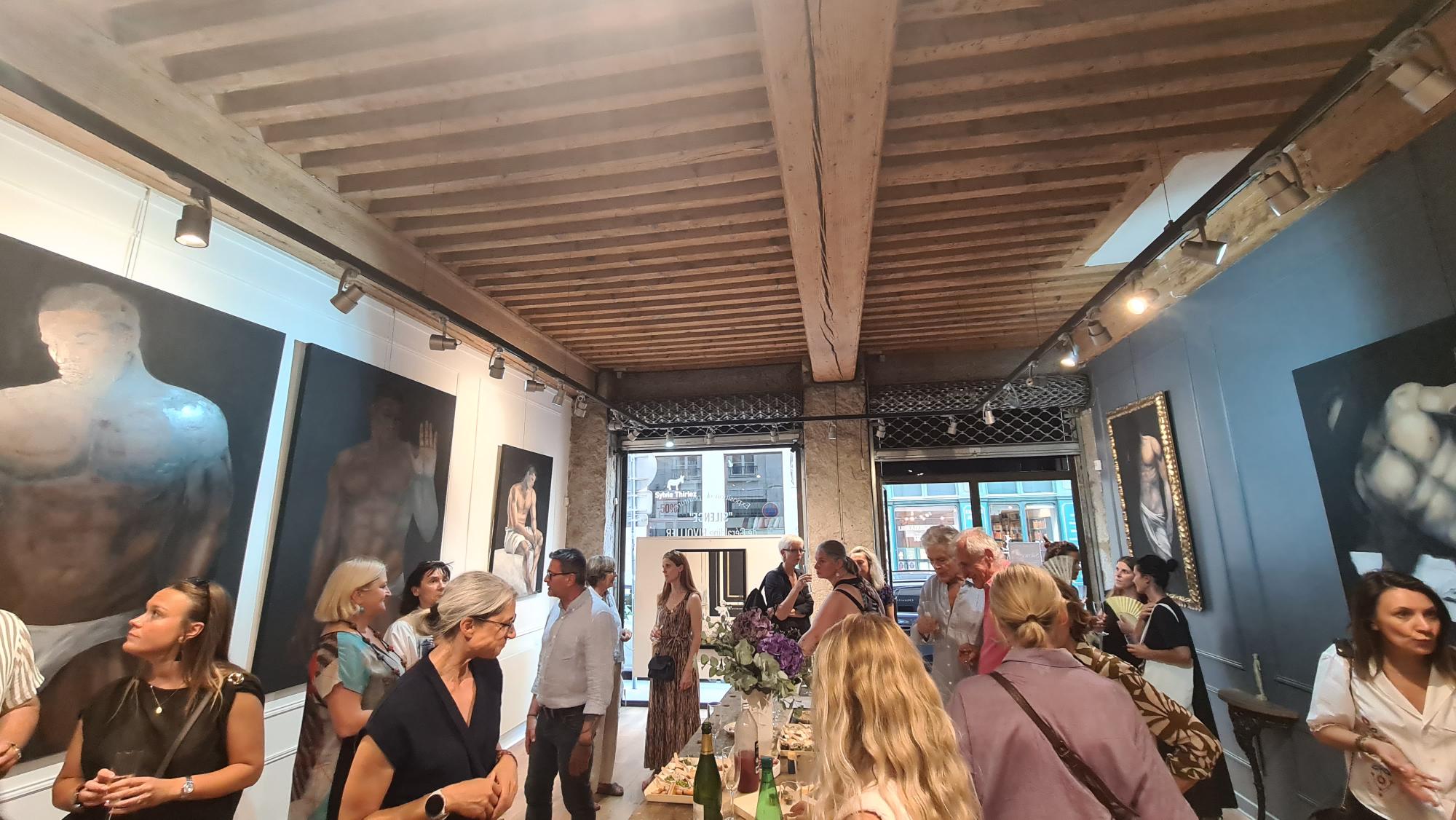 Vue intérieure lors d'un vernissage, poutres apparentes et grandes toiles