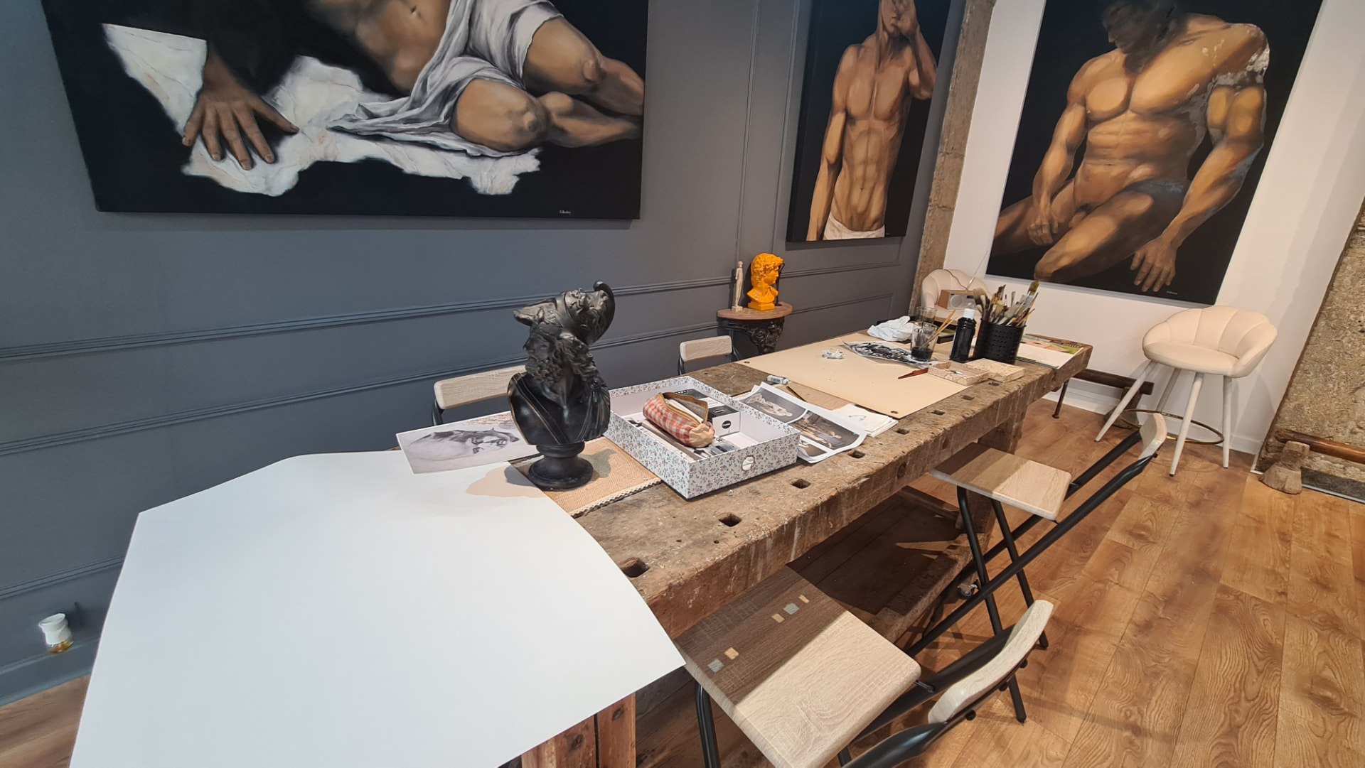 Vue de l'atelier : grande table de travail, bustes et toiles aux murs